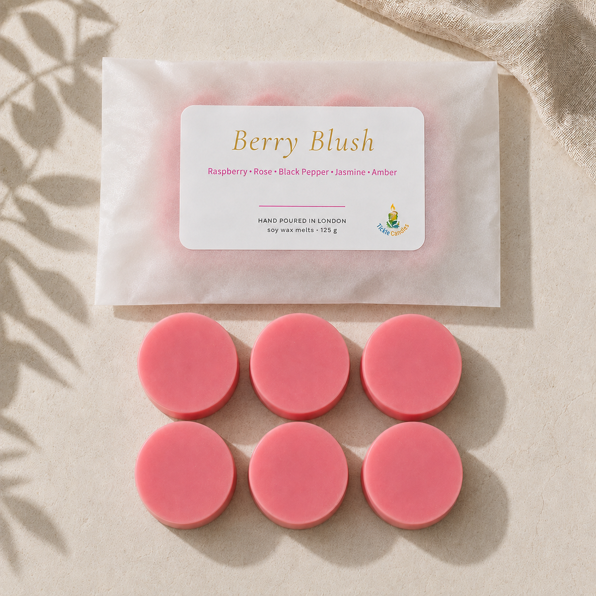 Top-down view of six pink Berry Blush 125g soy wax melts arranged below their labelled pouch in natural sunlight.