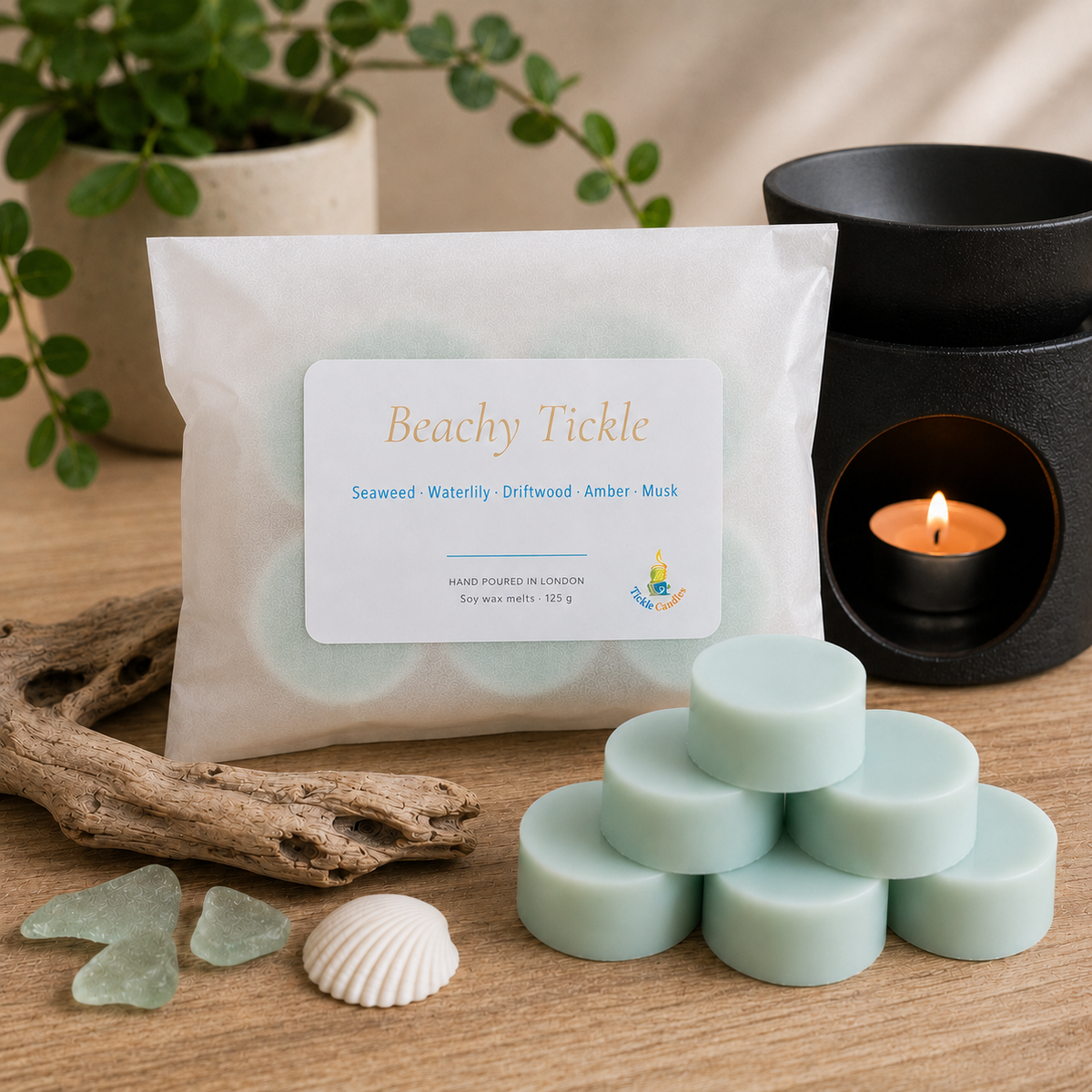 Pale blue Beachy Tickle 125g soy wax melts stacked beside their pouch and a lit black wax burner.