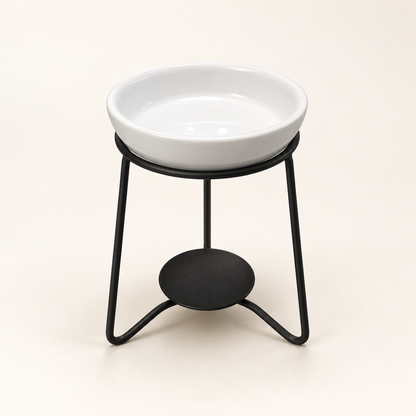 White ceramic wax melt burner on a black metal stand against a warm cream background