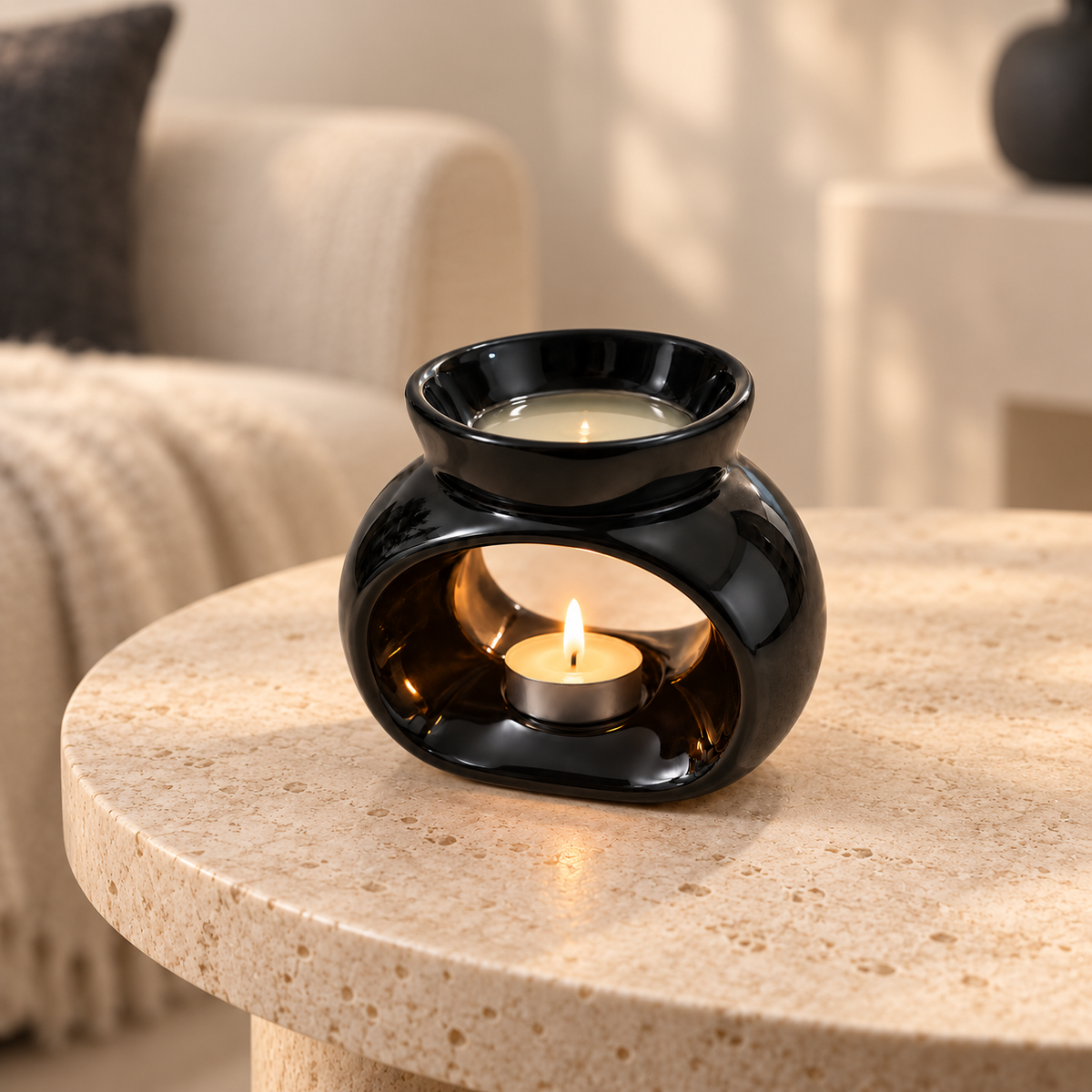 Black ceramic wax melt burner glowing on a cream stone table in a warm neutral living room.