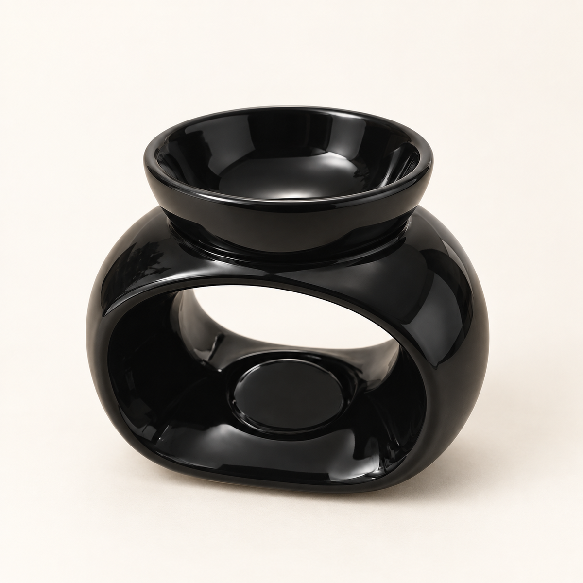 Glossy black oval ceramic wax melt burner on a warm cream background, shown from a three-quarter angle.